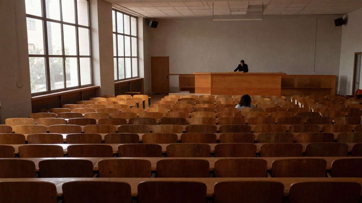 Imagen ilustrativa: un aula universitaria vacía con un atril y luz natural al fondo