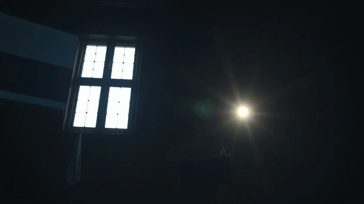 Illustrative image: an empty podium with a microphone in a dark room illuminated by natural light casting long shadows.