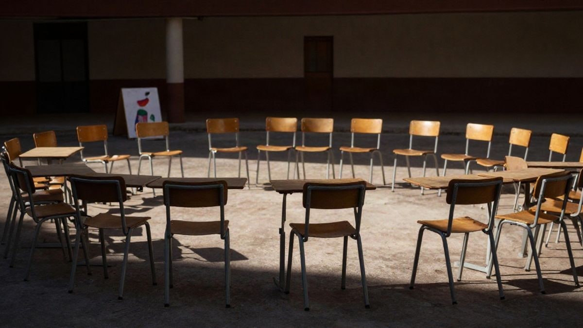 Illustrative image: schoolyard with empty chairs and a banner in the background under the afternoon light
