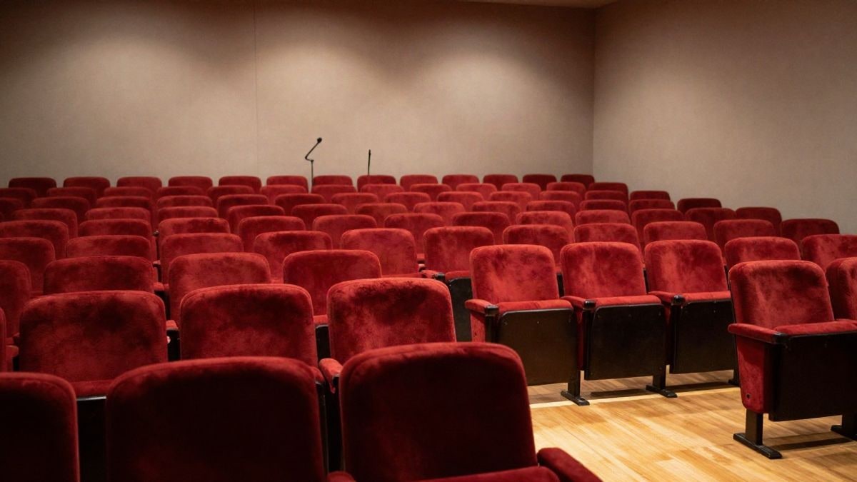 Imagen ilustrativa: un auditorio vacío con asientos de terciopelo rojo y luces cálidas en el escenario.