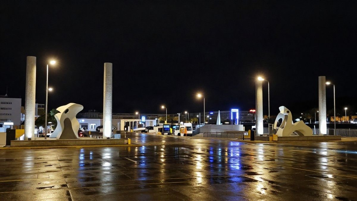 Illustrative image: abstract sculptures illuminated at the entrance of a port at night