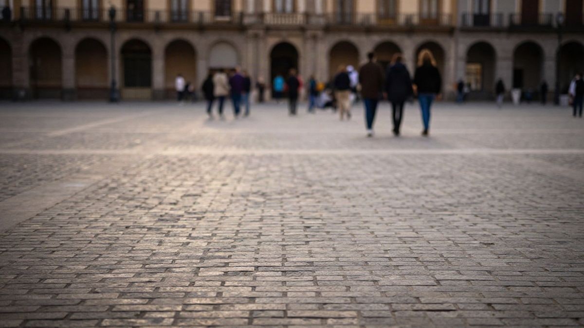 Imagen ilustrativa: plaza española genérica al atardecer con un grupo de personas al fondo y amplio espacio vacío