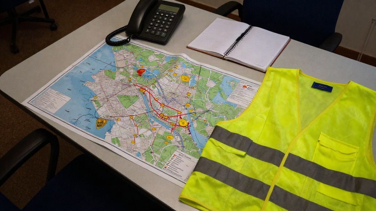 Illustrative image: overhead view of an emergency coordination table with map, phone, and reflective vest