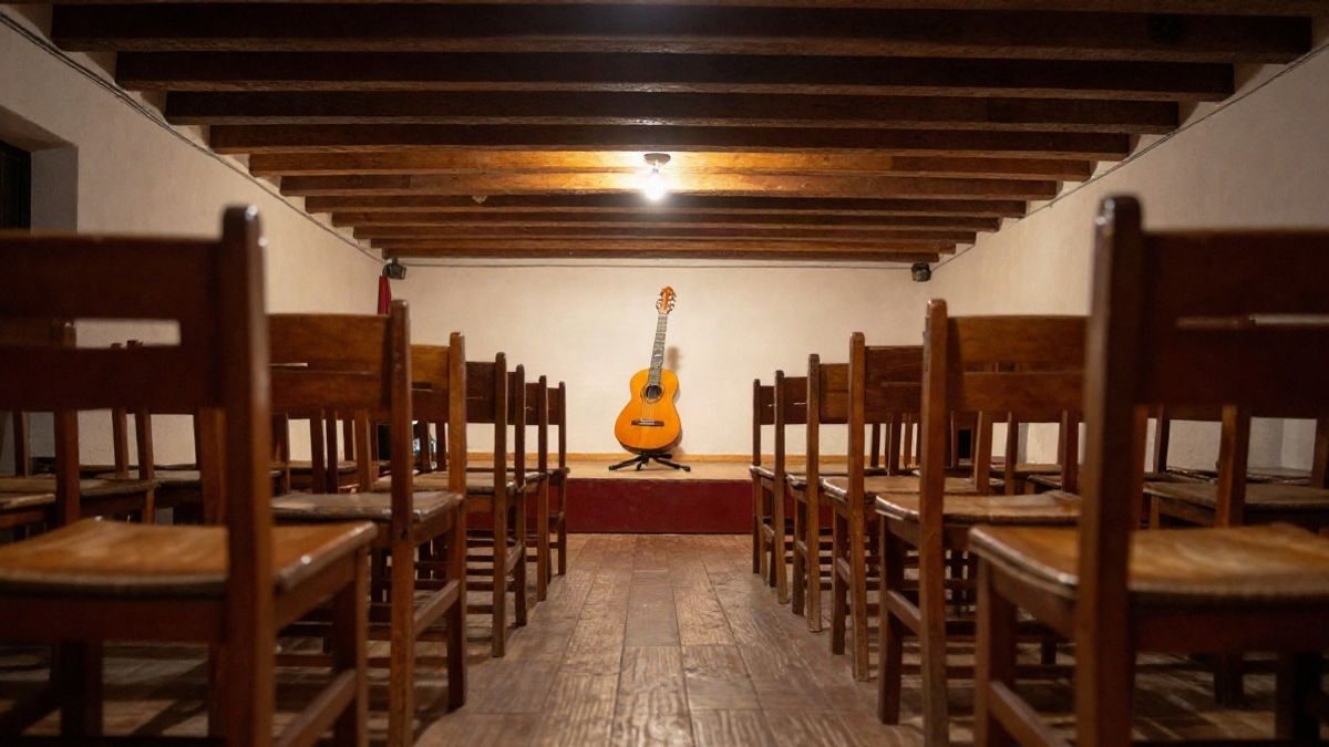 Illustrative image: interior of a flamenco peña with empty chairs and a Spanish guitar on a stand on stage