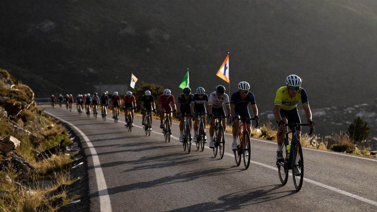 Imagen ilustrativa: un grupo de ciclistas en carretera de montaña al atardecer, con espectadores difuminados al fondo