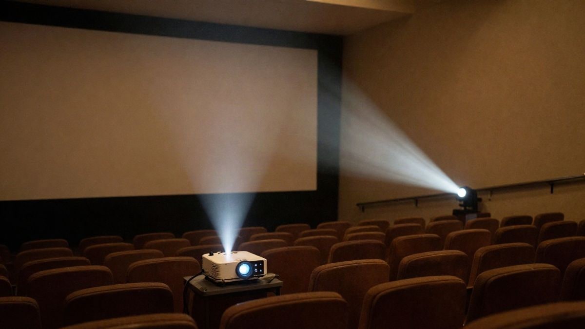 Illustrative image: a cinema projector illuminates a screen in an empty room, with seats in shadow.