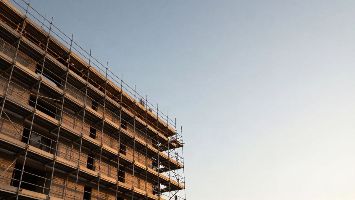 Imagen ilustrativa: edificio residencial en construcción con andamios bajo un cielo amplio