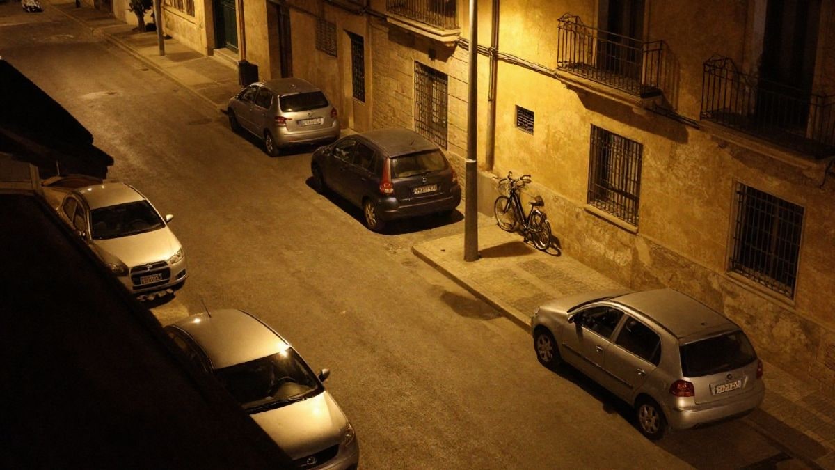 Illustrative image: overhead view of a quiet residential street at night with parked cars and a bicycle leaning against a wall