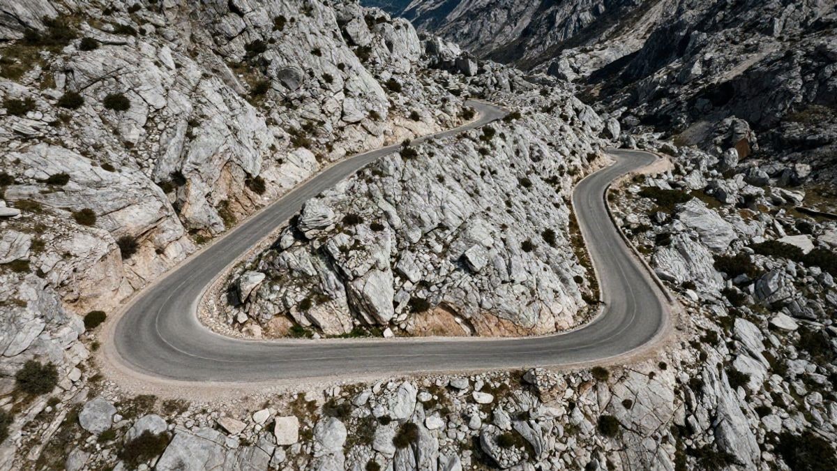 Imagen ilustrativa: vista cenital de una carretera de montaña recién asfaltada entre formaciones rocosas calizas