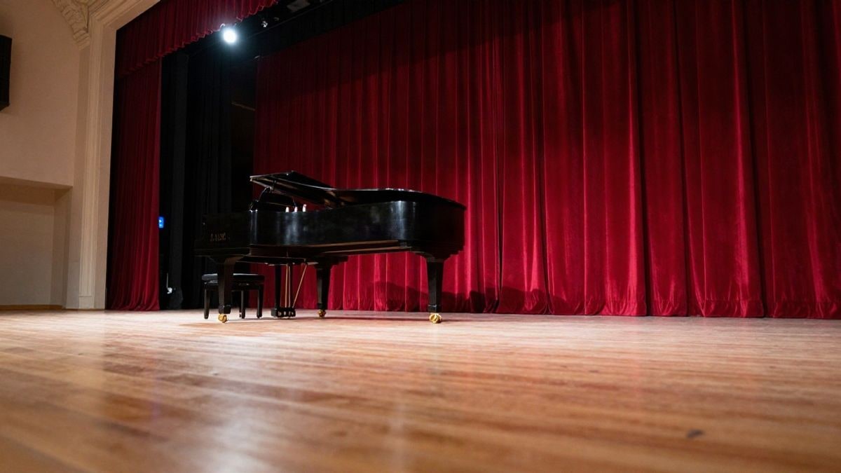 Illustrative image: empty theatre stage with a grand piano and spotlight