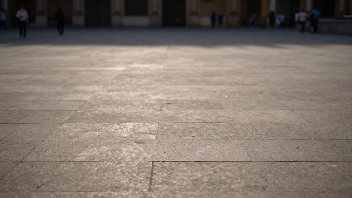 Imagen ilustrativa: plaza urbana con figuras lejanas de espaldas y espacio negativo