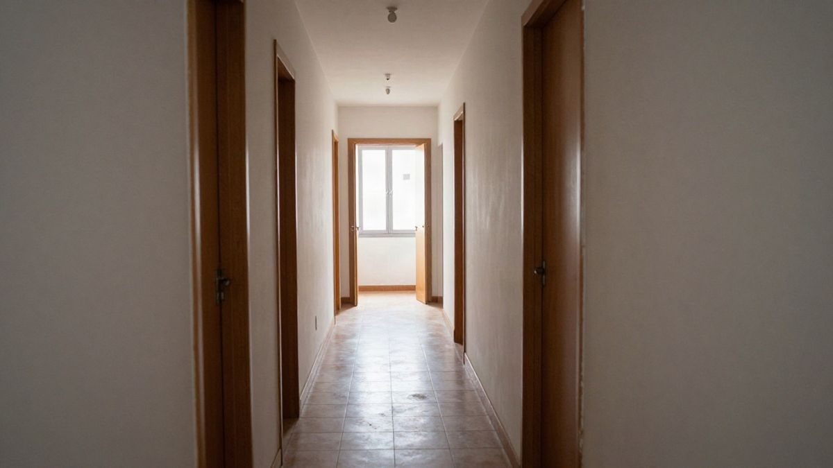 Illustrative image: corridor of a residential building with ajar doors and natural light in the background