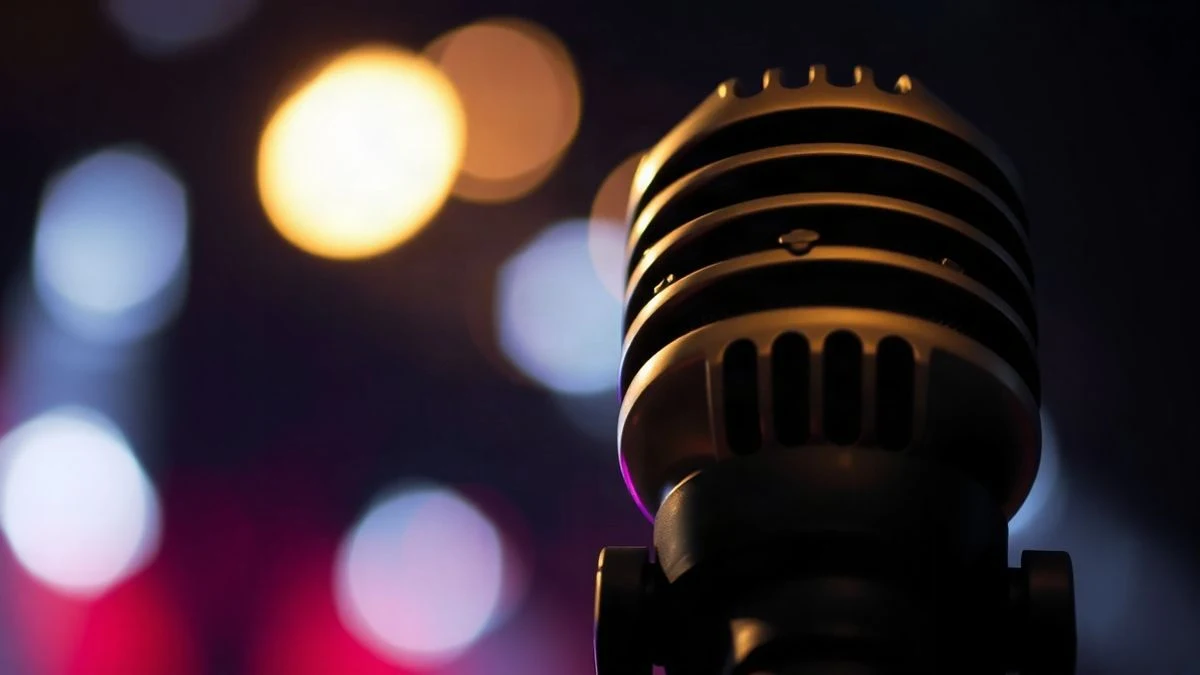 Imagen ilustrativa: primer plano de un micrófono con luces de fondo desenfocadas, evocando un concierto.