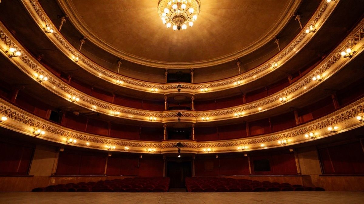 Imagen ilustrativa: escenario de teatro vacío con cortinas rojas y balcones, visto desde un ángulo bajo