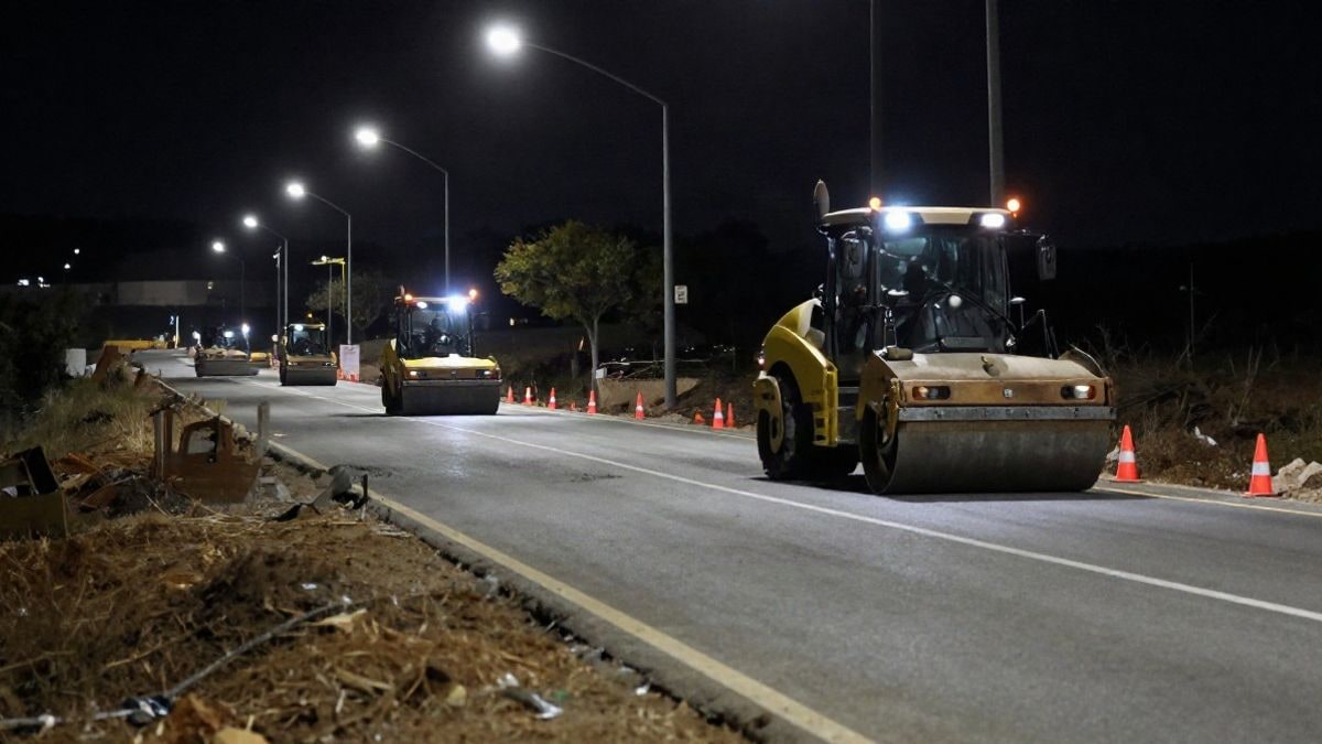 Illustrative image: stretch of rural road under construction illuminated by streetlights and night spotlights
