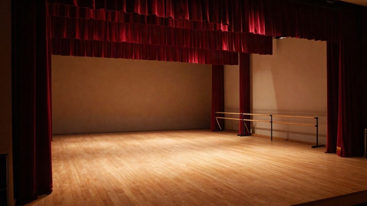 Imagen ilustrativa: un escenario teatral vacío con luces cálidas y telón rojo, listo para un espectáculo de danza.