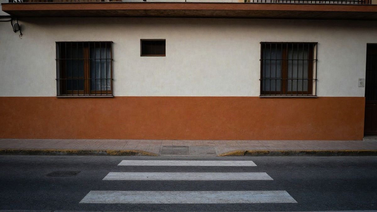Imagen ilustrativa: fachada de un colegio recién pintada y un paso de peatones sin personas, en una calle vacía.