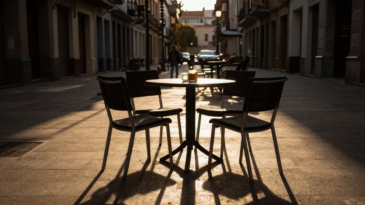 Imagen ilustrativa: sillas vacías y tazas de café en una plaza al atardecer