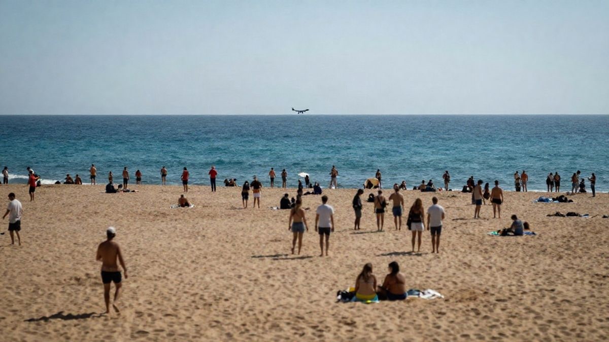 Imagen ilustrativa: Vista aérea de una playa mediterránea abarrotada de gente y sombrillas, con un avión pequeño dibujando una maniobra en el cielo.